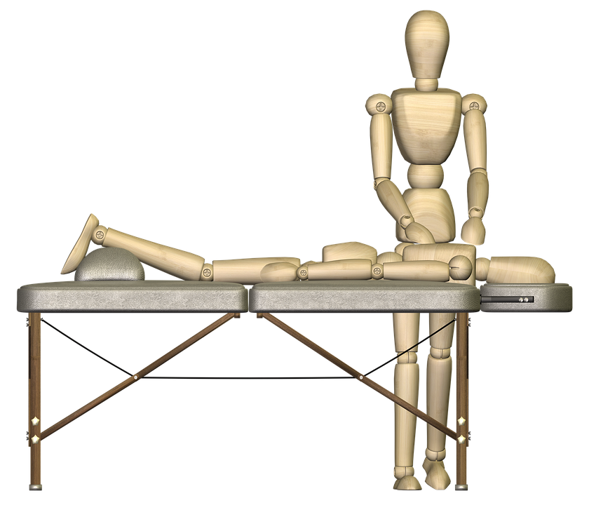 A wooden mannequin figure giving a treatment to another lying on a treatment table